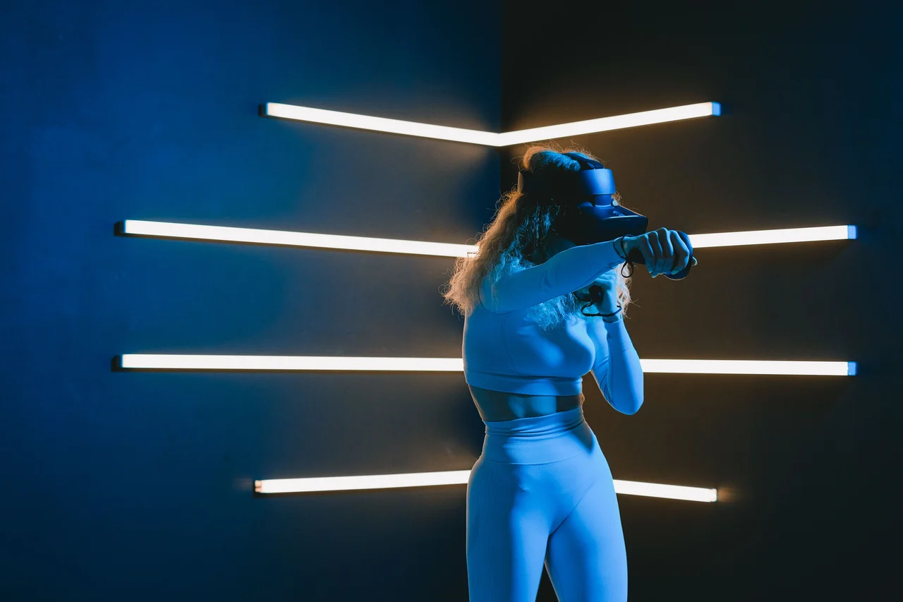 A woman exploring virtual reality with a headset in a blue-lit room, photographed by SHVETS production